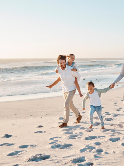 Happy family walking on the beach together. Young caucasian family relaxing together on the beach. .