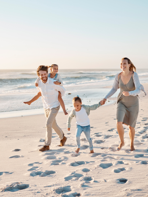 Happy family walking on the beach together. Young caucasian family relaxing together on the beach. .