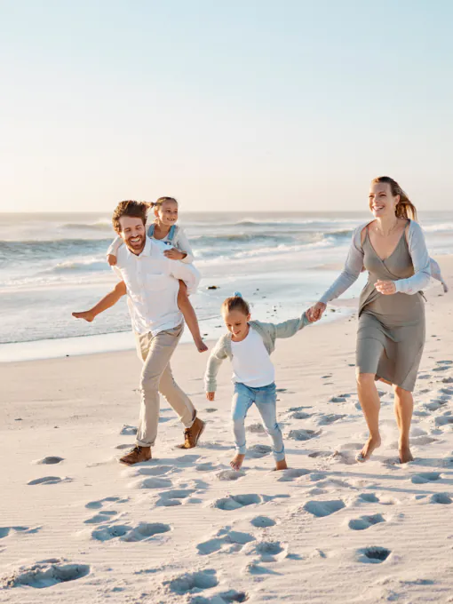 Happy family walking on the beach together. Young caucasian family relaxing together on the beach. .
